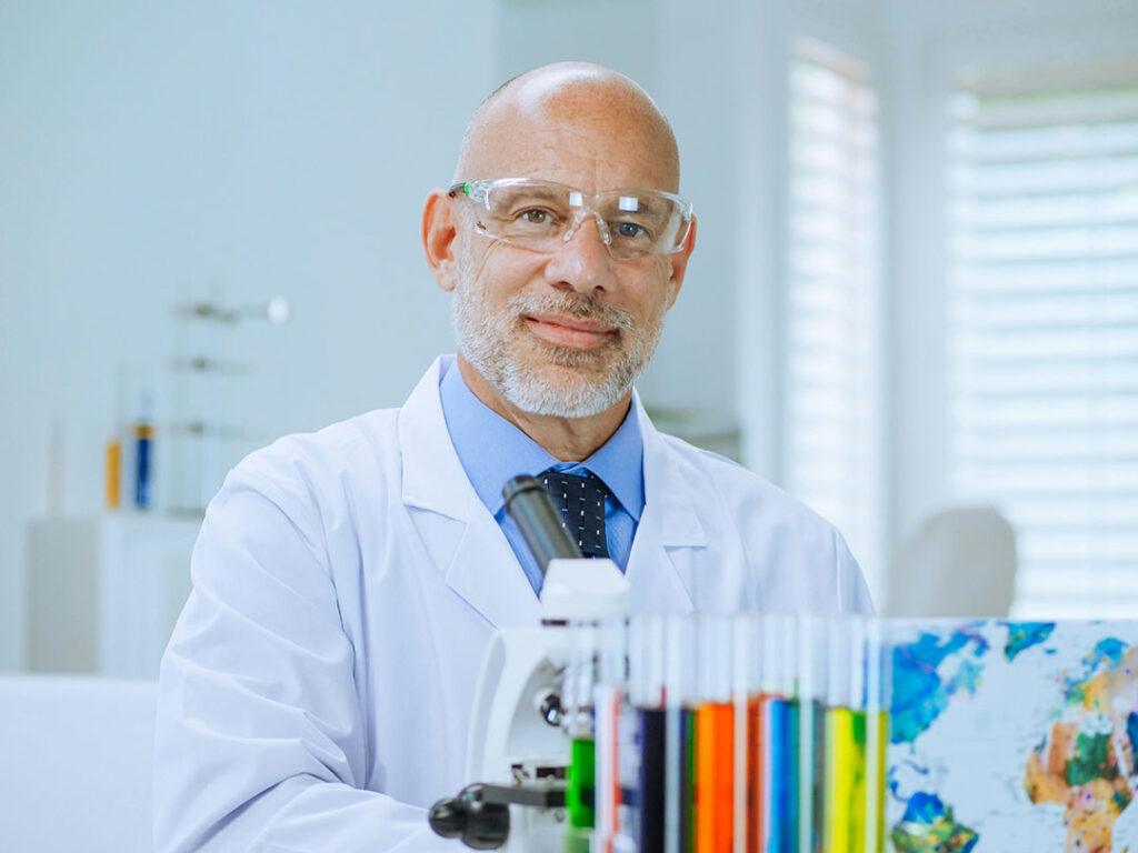 smiling man wearing safety glasses and white coat in medical office
